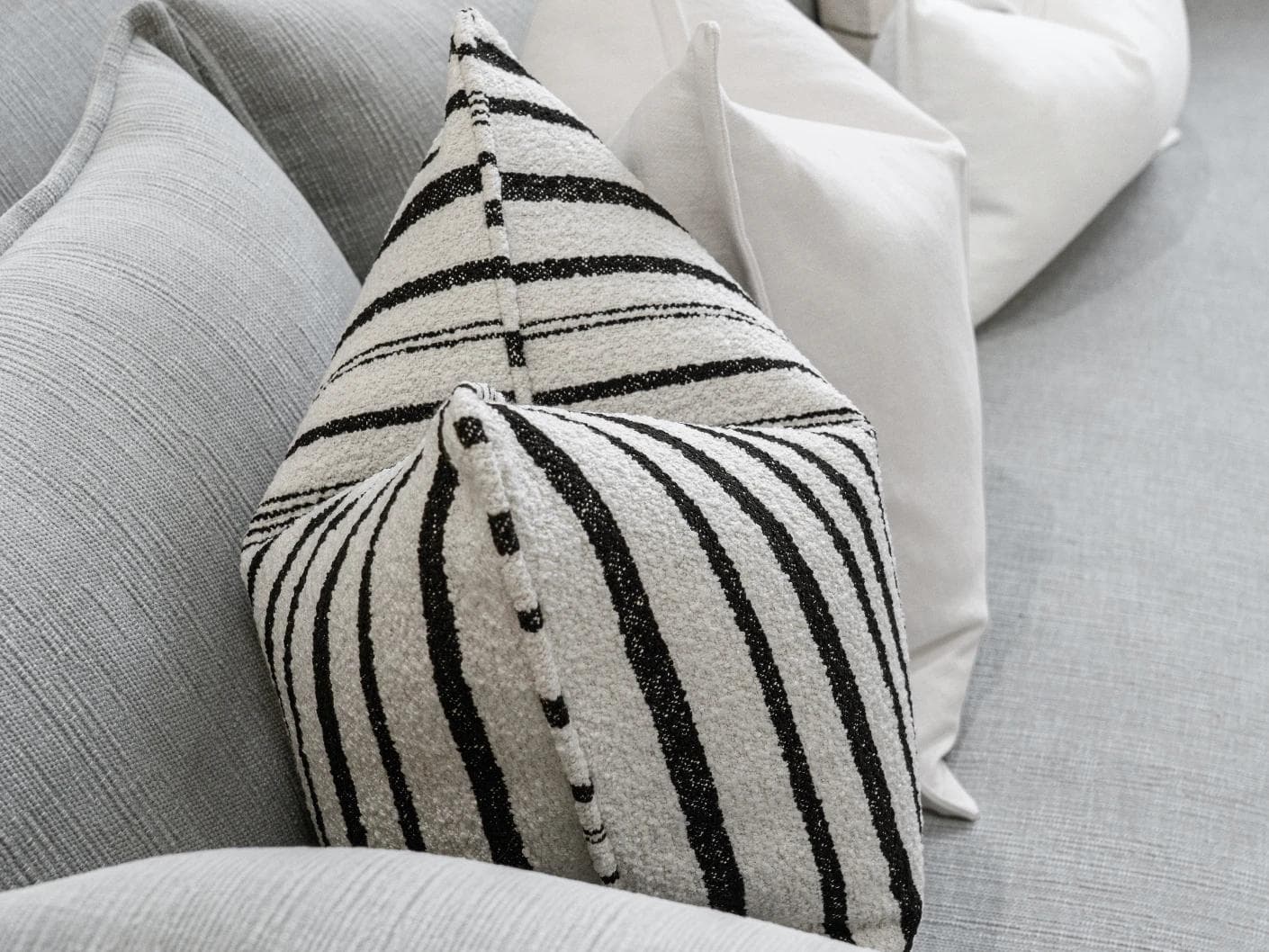 Amshi Bundle cushion in ivory, white and charcoal, shown in a lifestyle left view as image 7