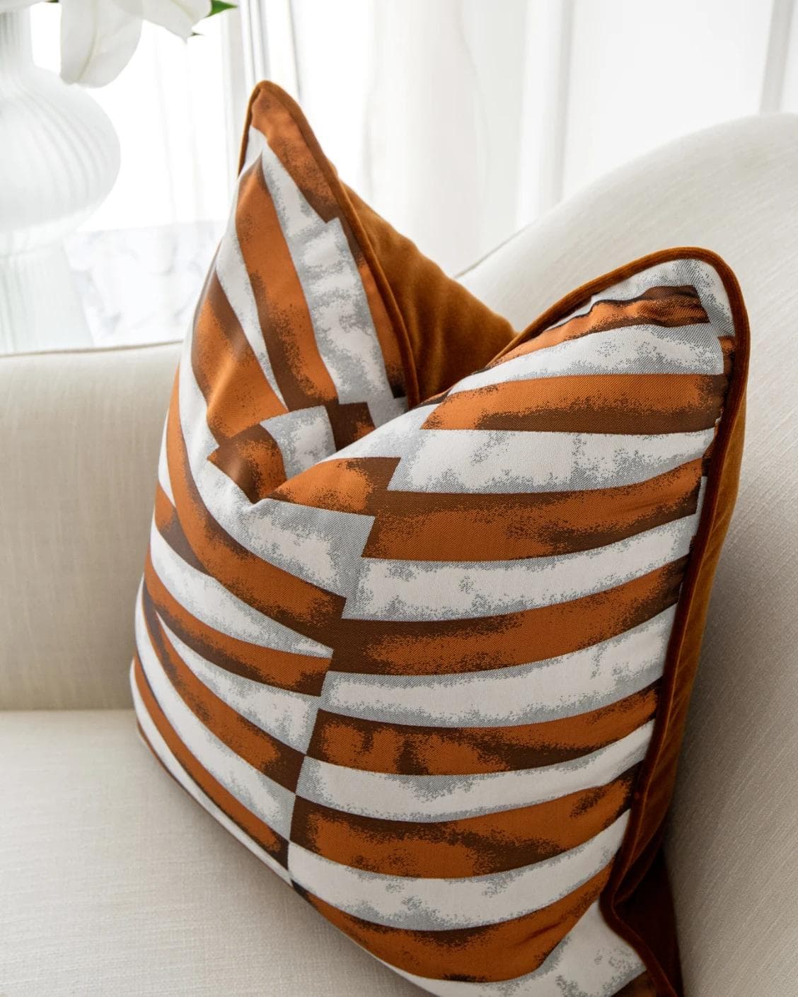 Carlie Hodler cushion in orange and white, shown in a lifestyle top view as image 5