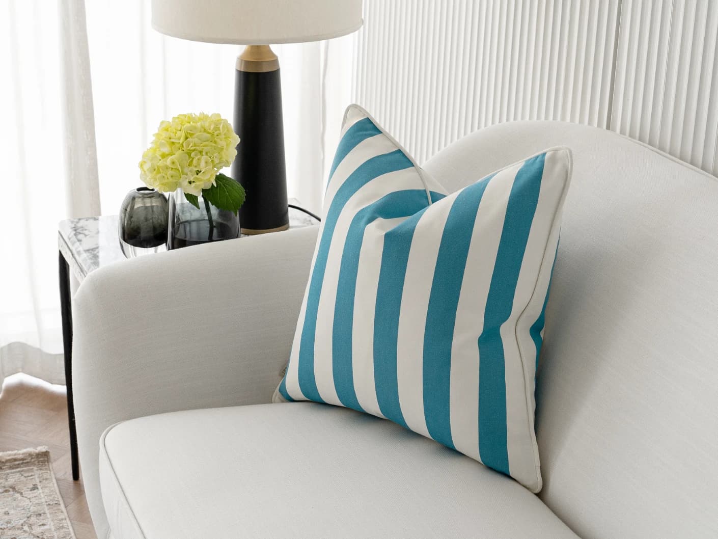Aelia Azure single cushions in azure, blue and soft ivory, shown in a lifestyle right view
