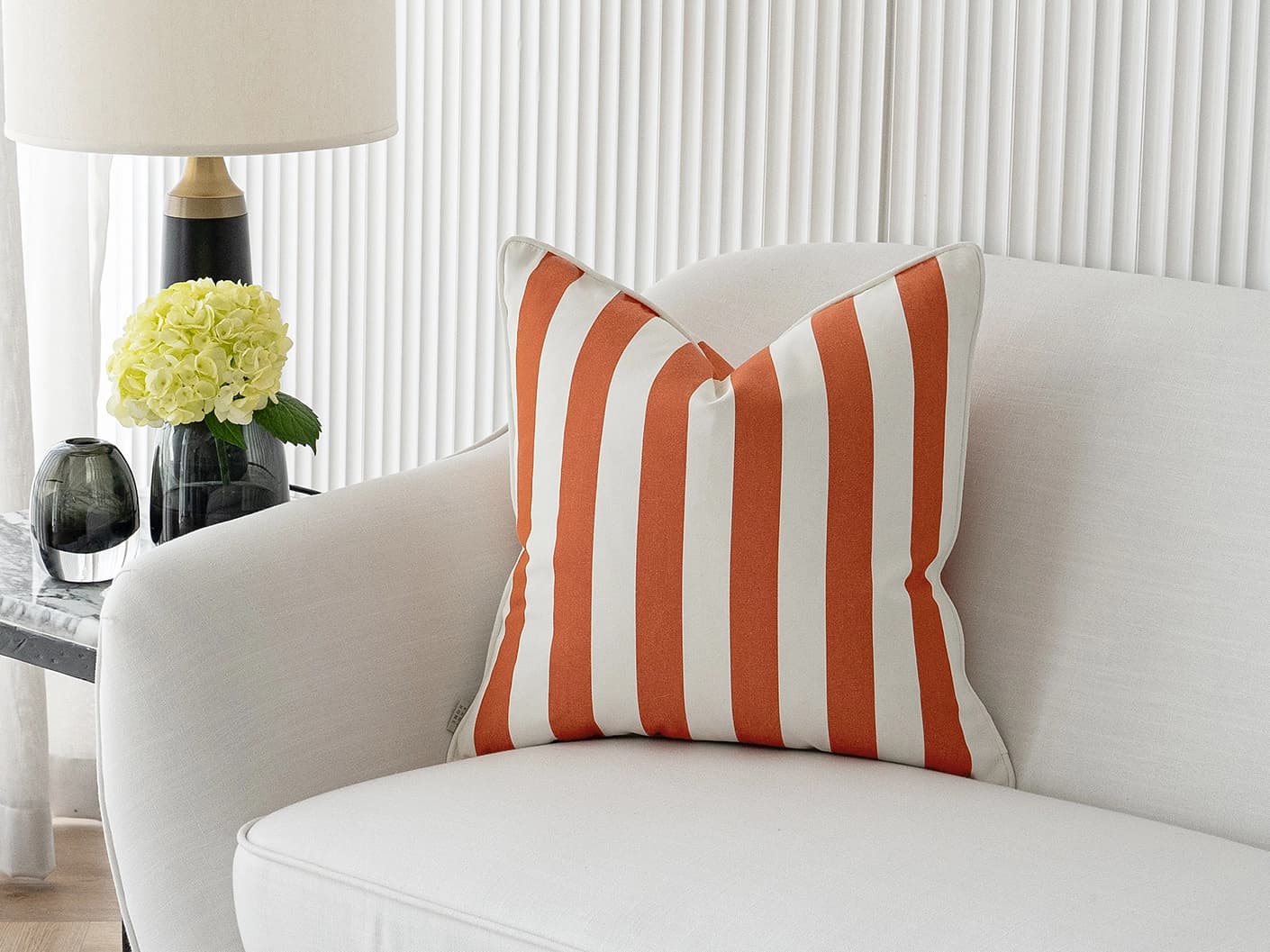 Aelia Coral single cushions in coral and orange, shown in a lifestyle front view
