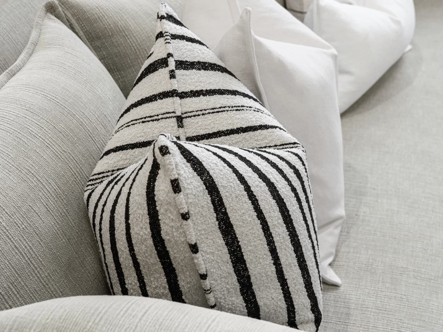 Amshi Bundle bundle cushions in ivory, white and charcoal, shown in a lifestyle front view