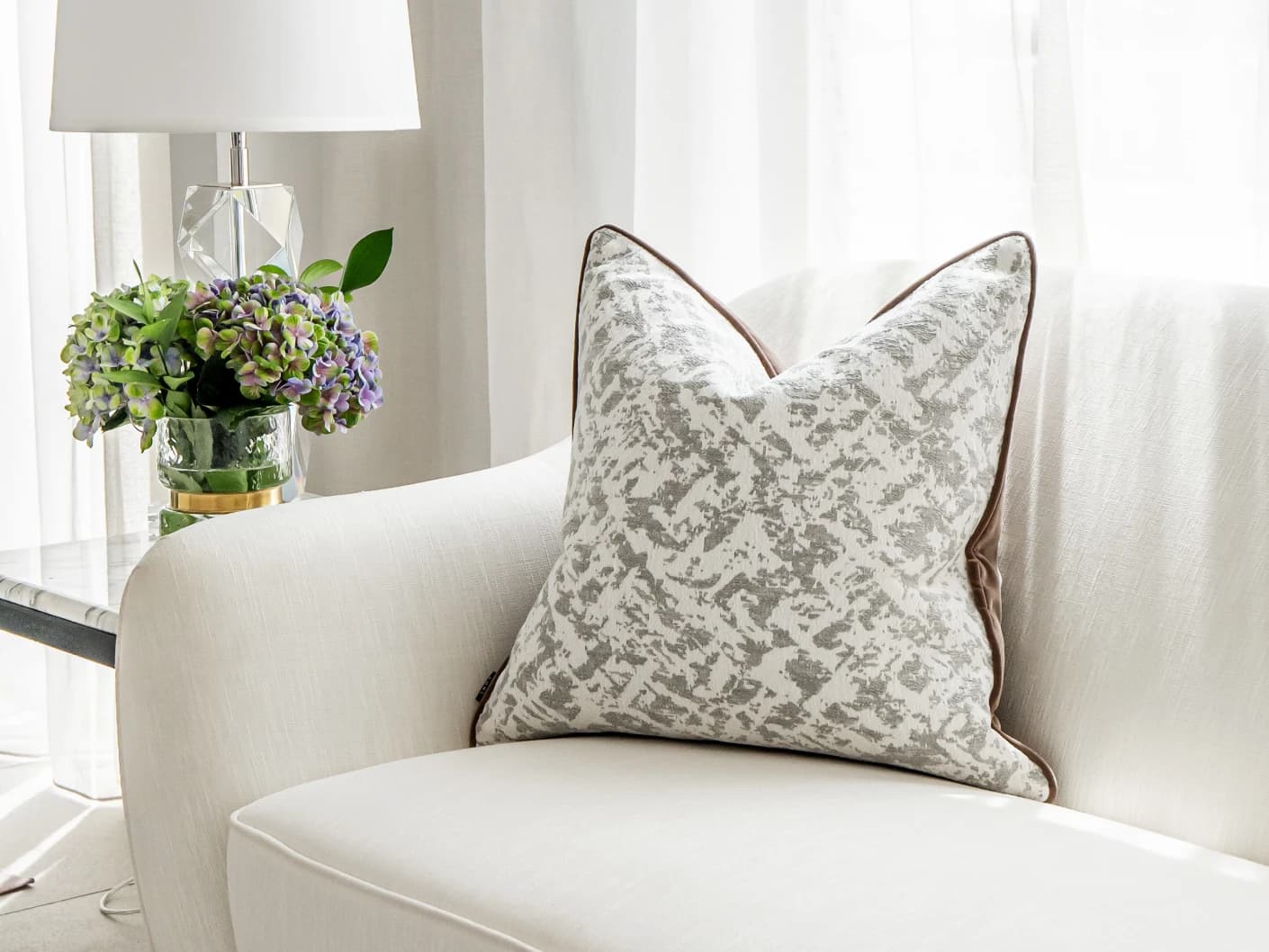 Arcie Laurent single cushions in white and silver, shown in a lifestyle front view