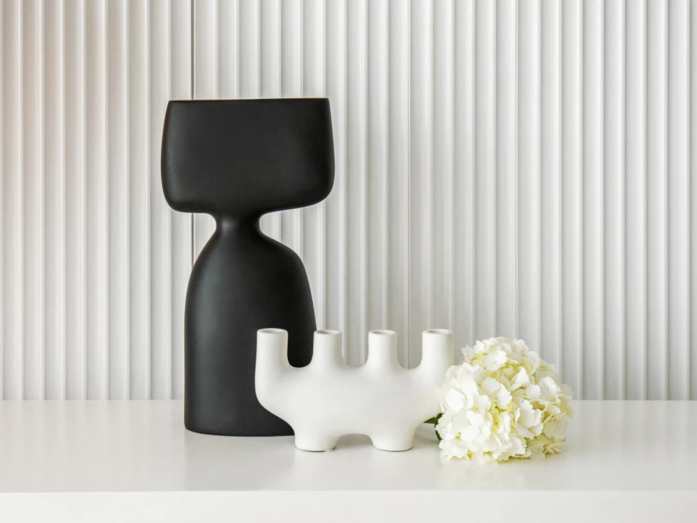 Berta Arneson vases in white and black, shown in a lifestyle front view