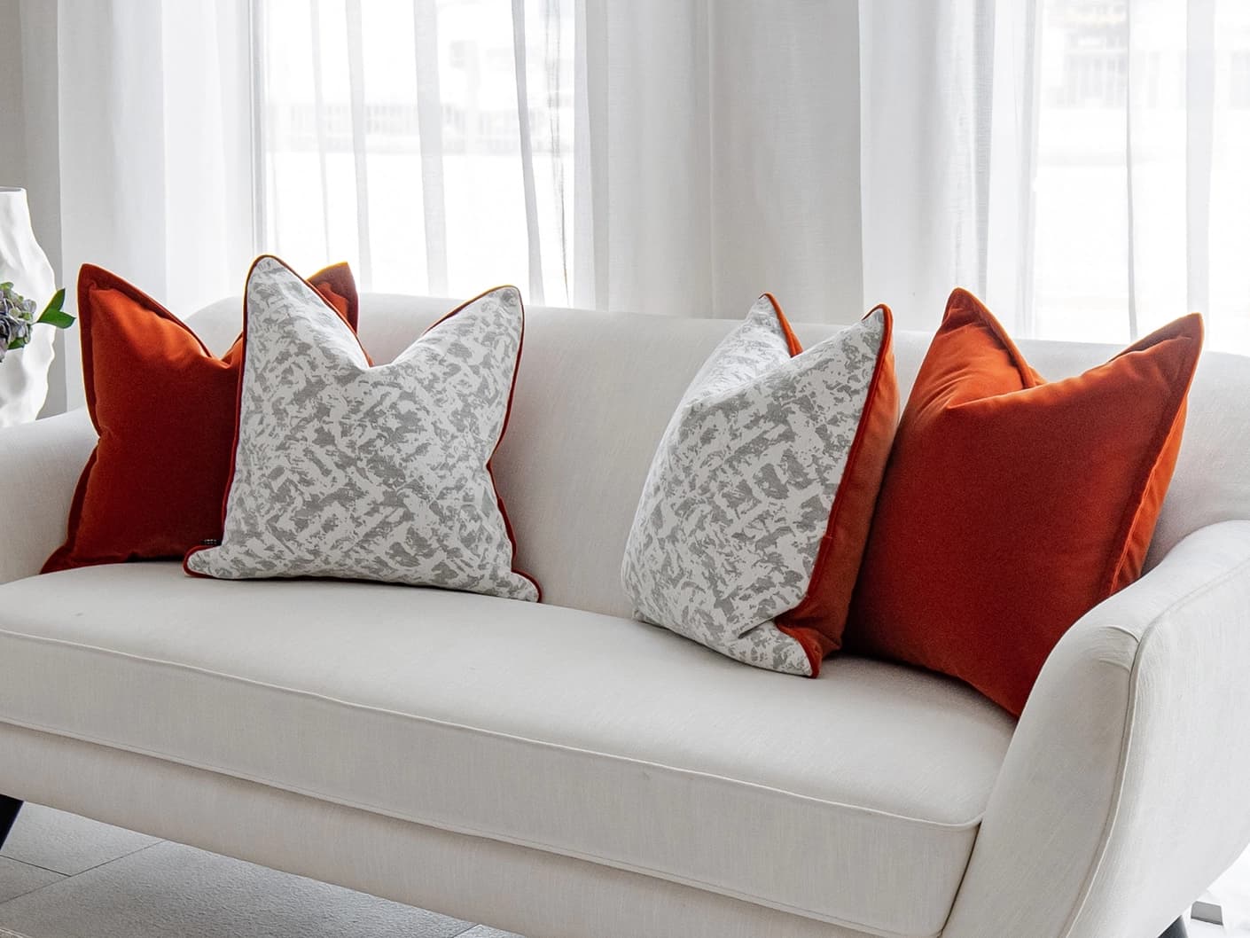 Braddy Bundle bundle cushions in tan, orange, white and silver, shown in a lifestyle front view