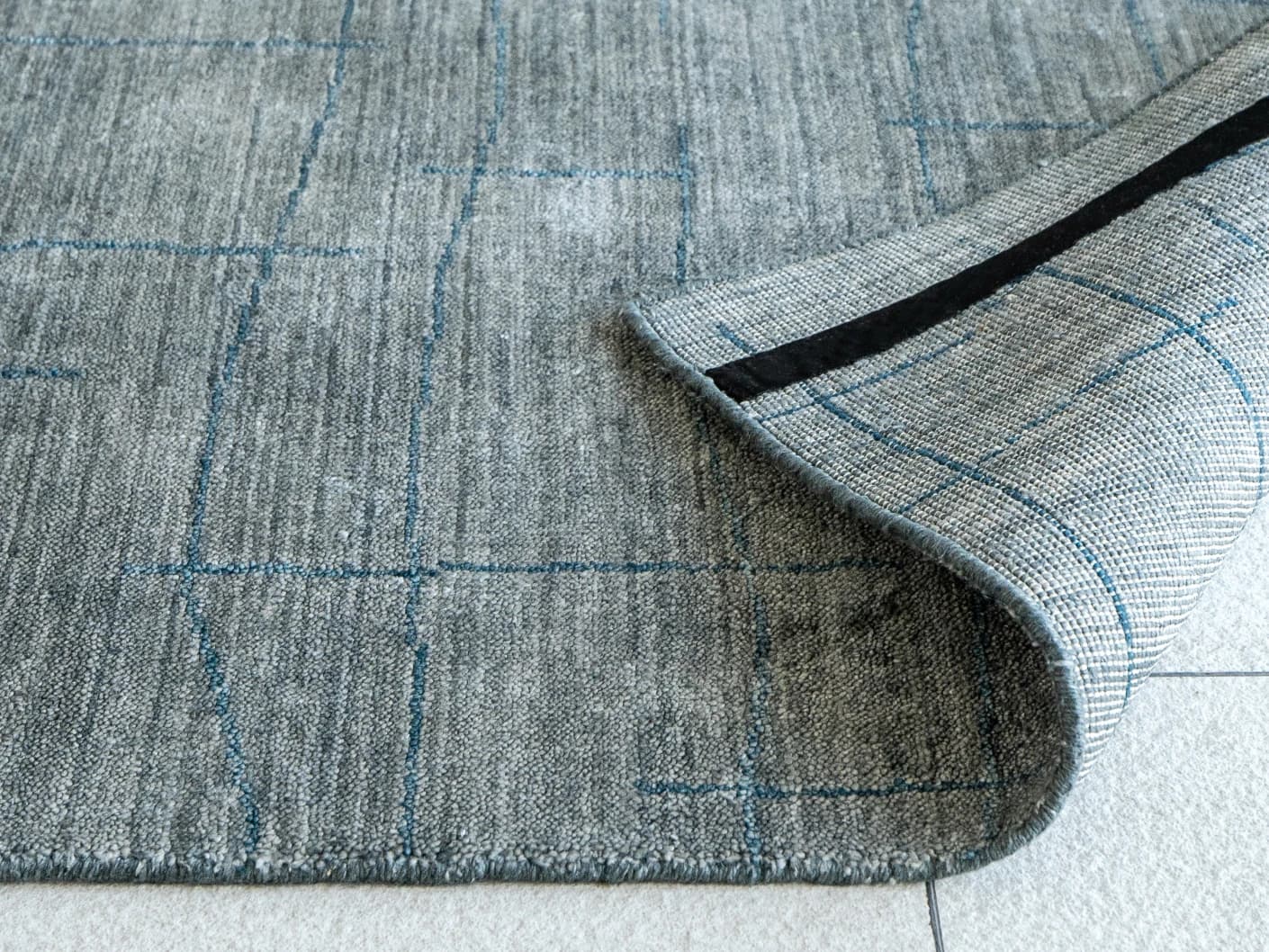 Caleb Ashton Round carpets in grey, teal and blue, shown in a product close-up view