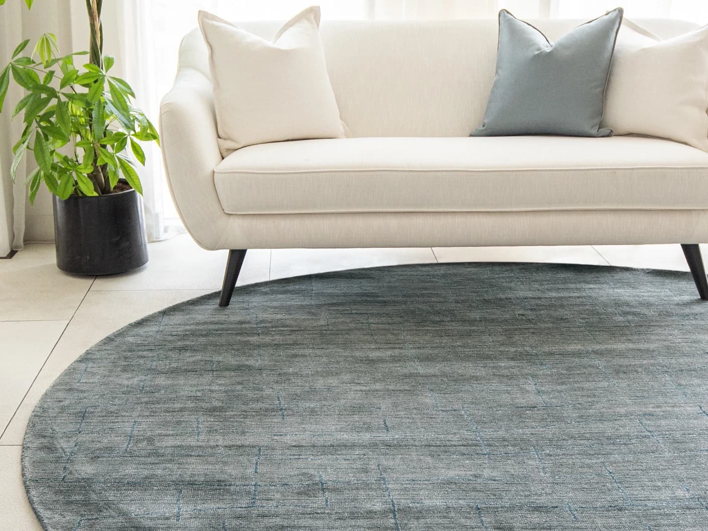 Caleb Ashton Round carpet in grey, teal and blue, shown in a lifestyle front view