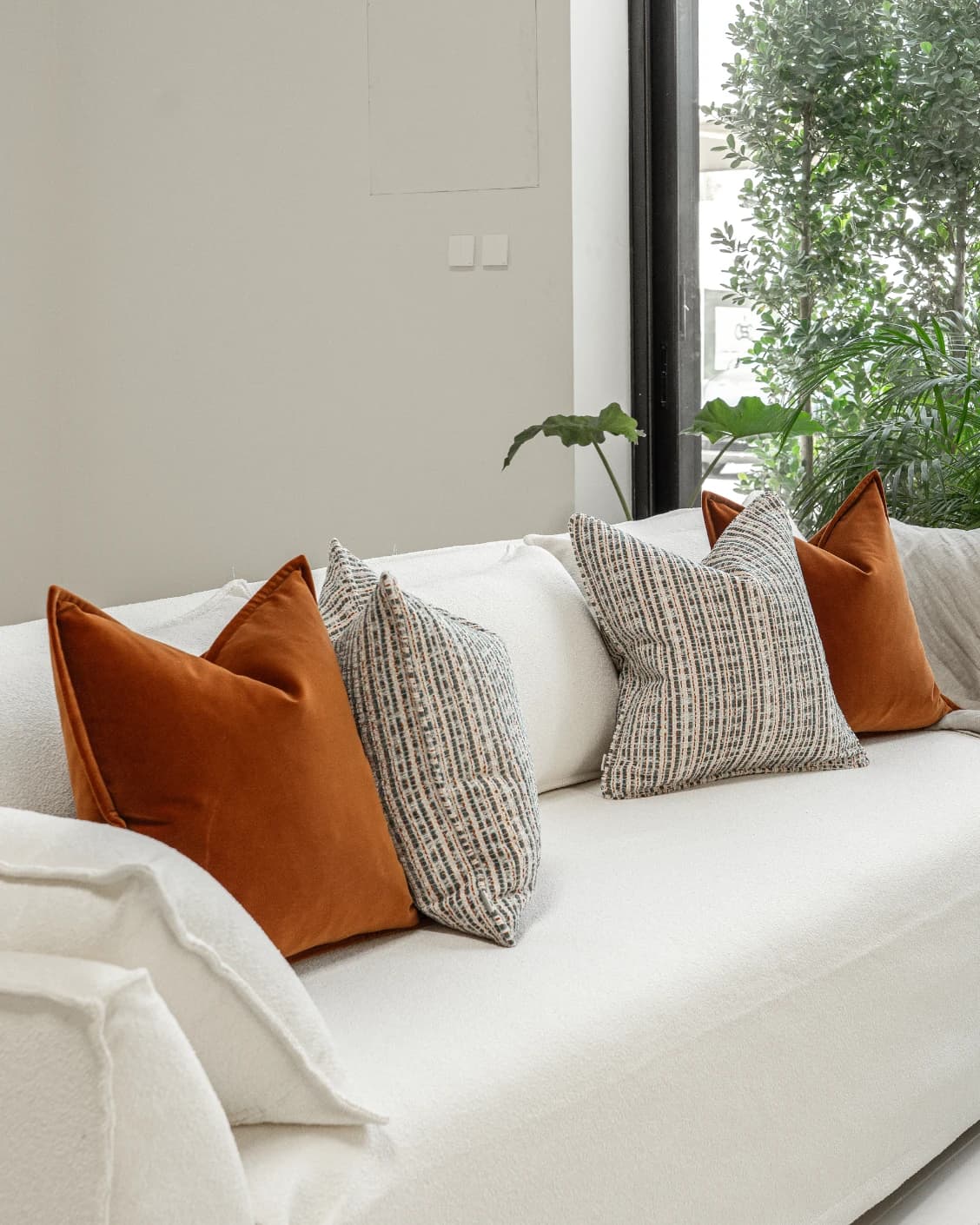 Cashwin Bundle cushion in cream and rust, shown in a lifestyle left view as image 2