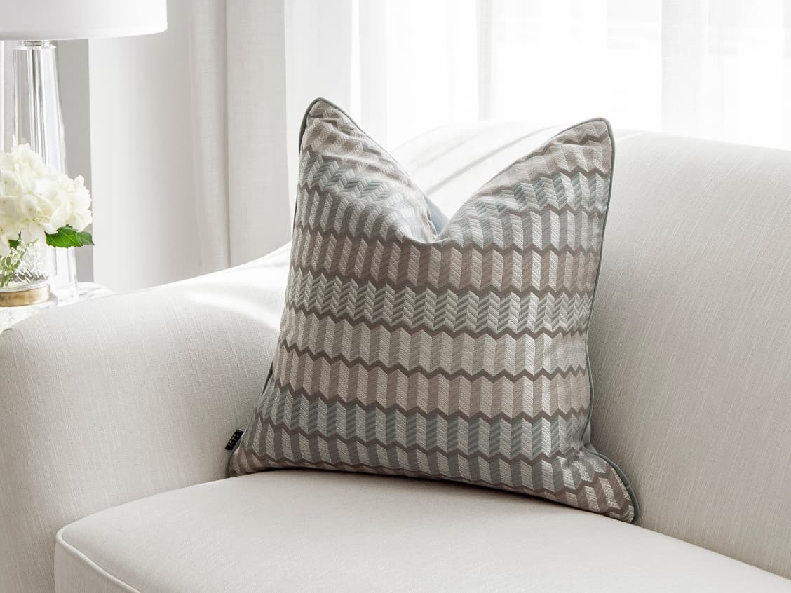 Cecilia Canova single cushions in silver, blue and multicolour, shown in a lifestyle front view