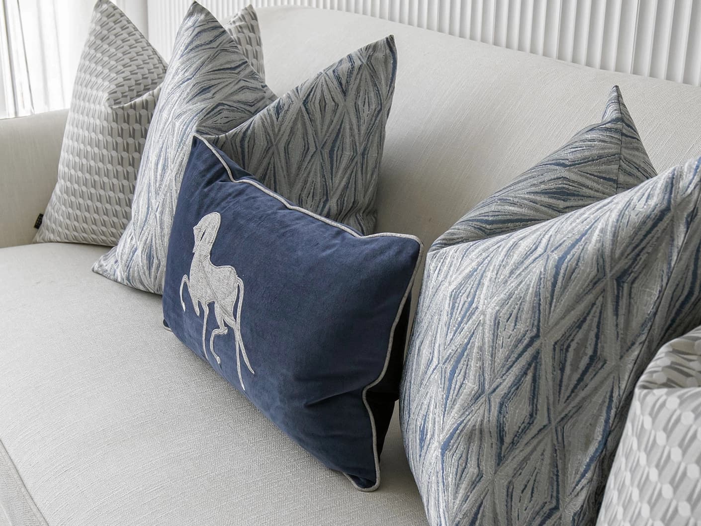 Edwin Bundle bundle cushions in blue, silver and white, shown in a lifestyle right view