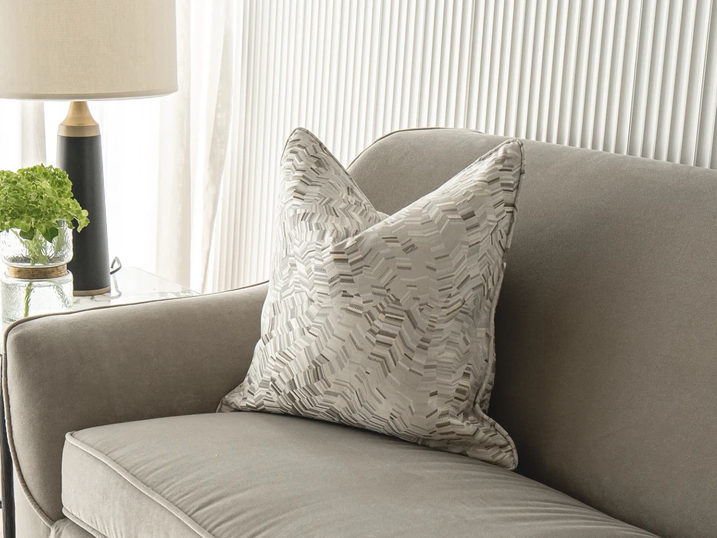 Faye Hodler single cushions in silver and grey, shown in a lifestyle front view