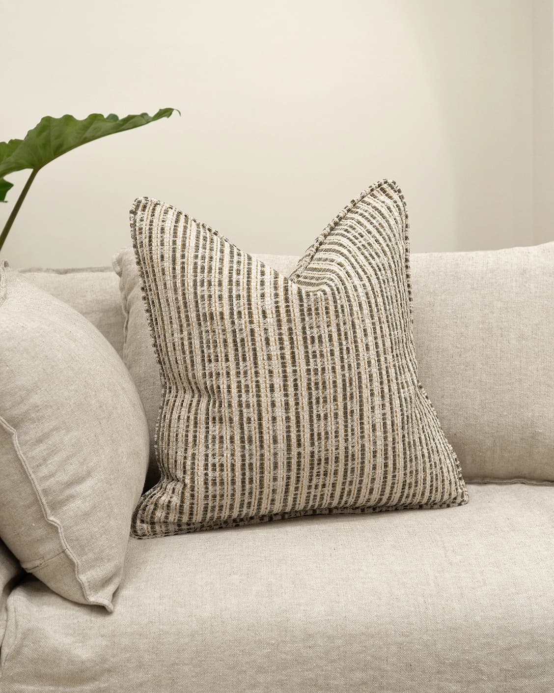 Izzy Olive cushion in ivory, shown in a lifestyle front view as image 2