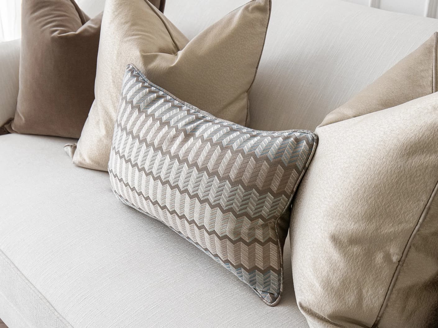 James Bundle bundle cushions in silver, blue, brown and beige, shown in a lifestyle front view
