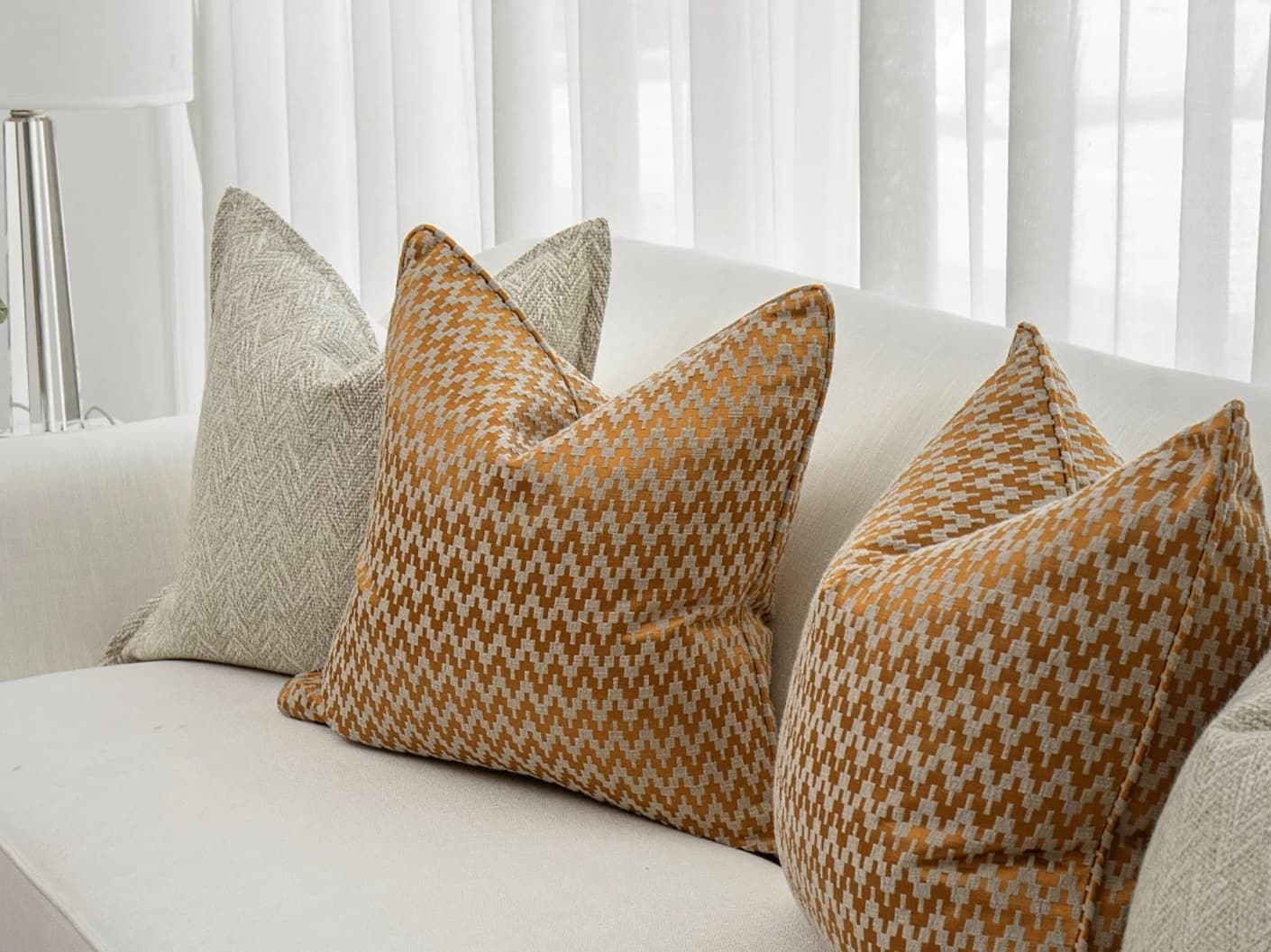 Janna Bundle bundle cushions in orange and beige, shown in a lifestyle front view