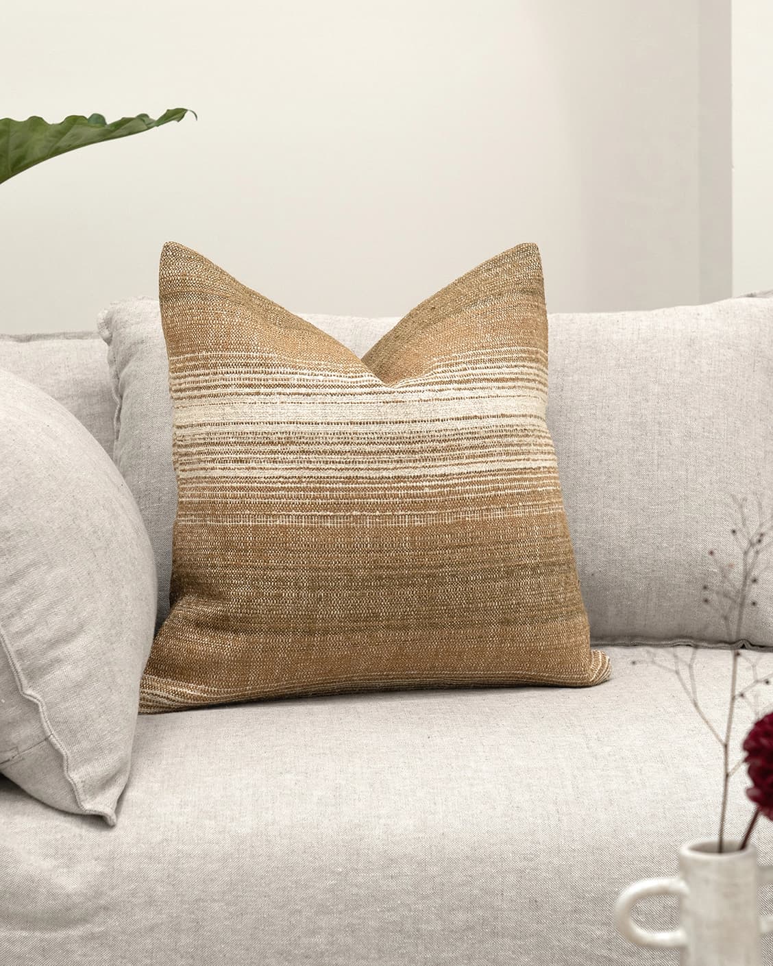 Lia Ember cushion in brown, shown in a lifestyle front view as image 2