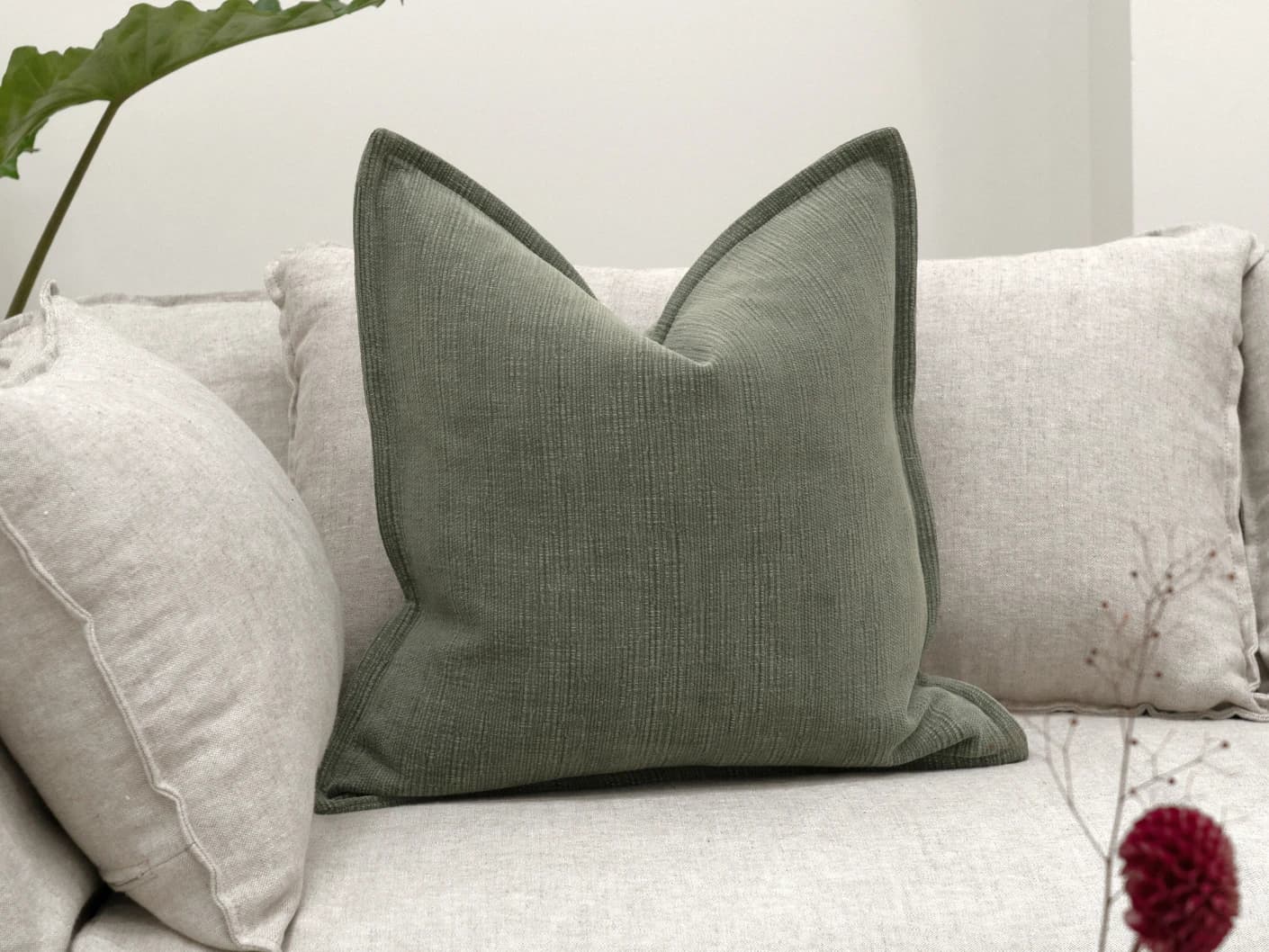 Macey Jade single cushions in grey and green, shown in a lifestyle front view