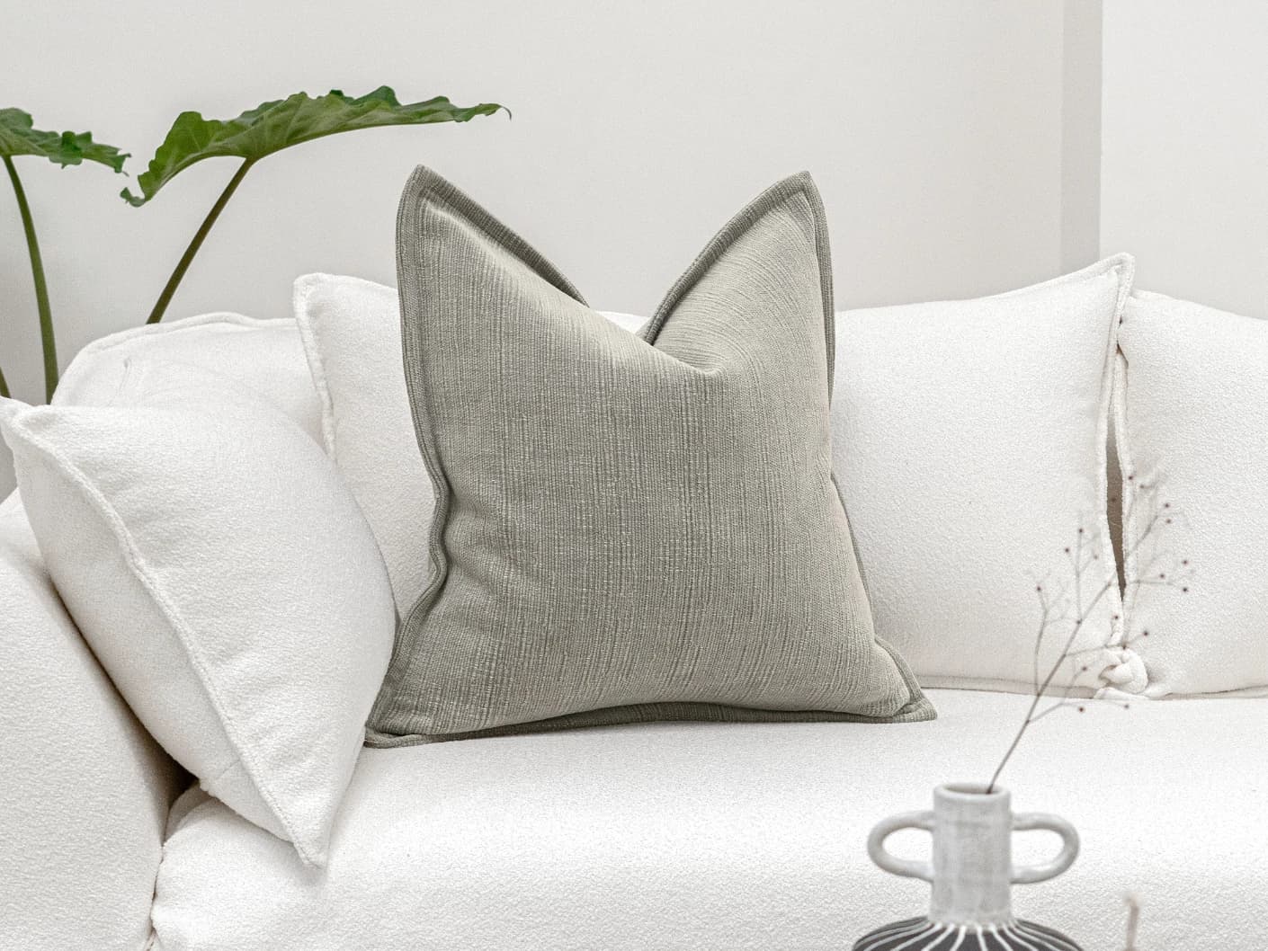 Macey Laurent single cushions in grey, shown in a lifestyle front view