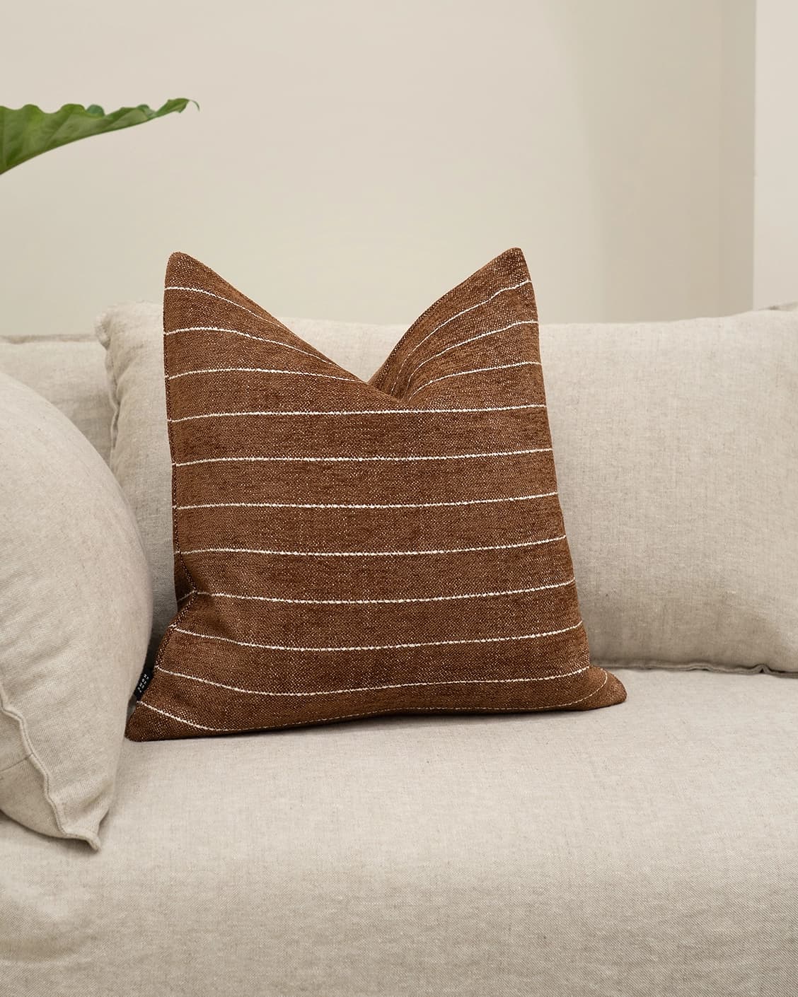 Noa Rust cushion in white and brown, shown in a lifestyle front view as image 2