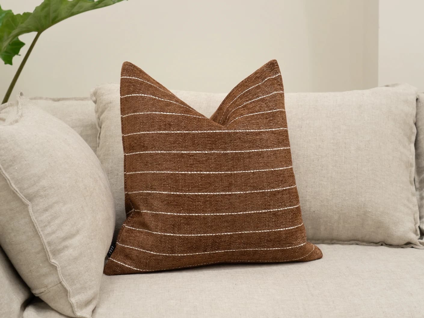Noa Rust single cushions in rust, white and brown, shown in a lifestyle front view