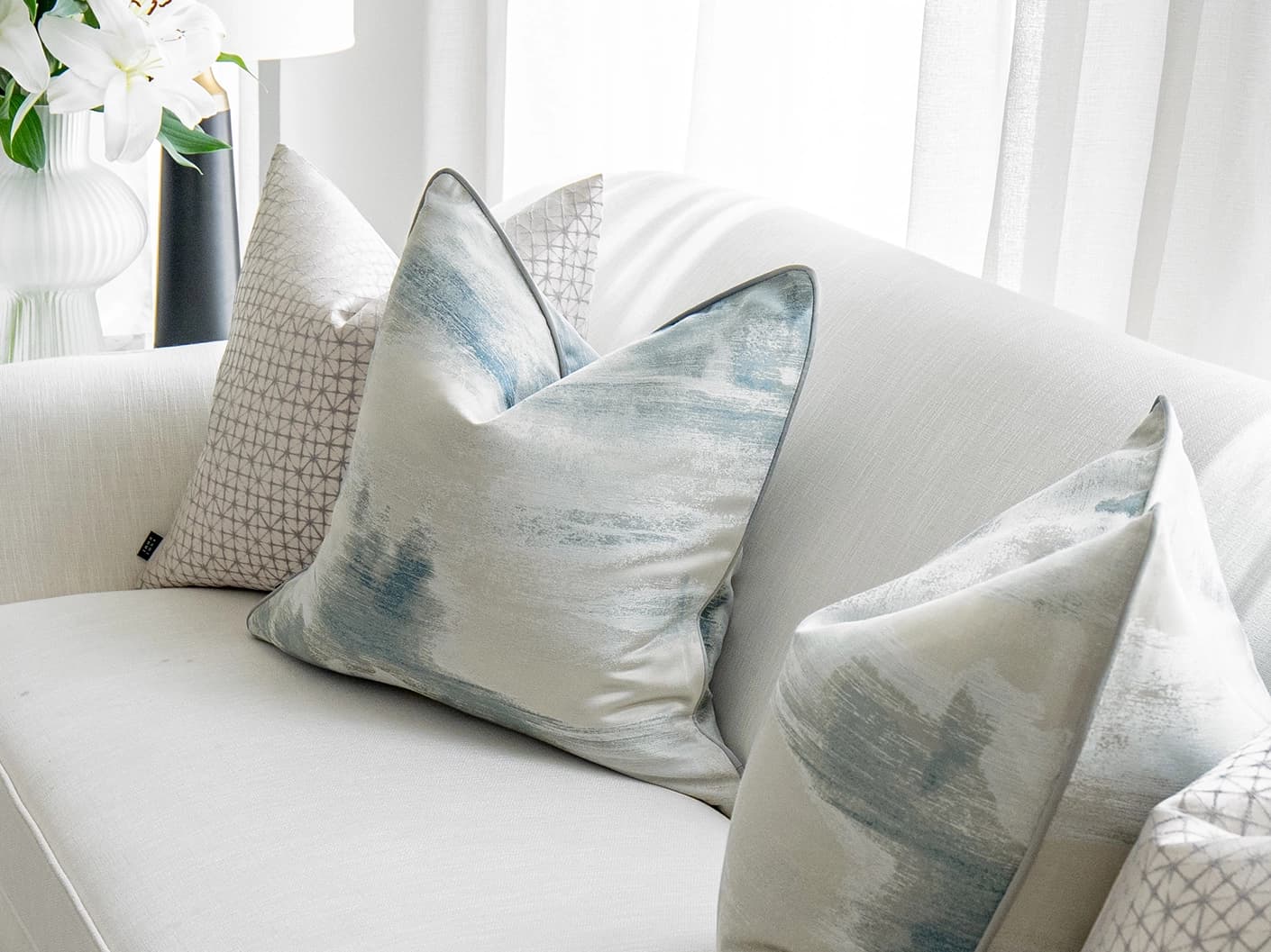Orlan Bundle bundle cushions in blue, silver and white, shown in a lifestyle front view