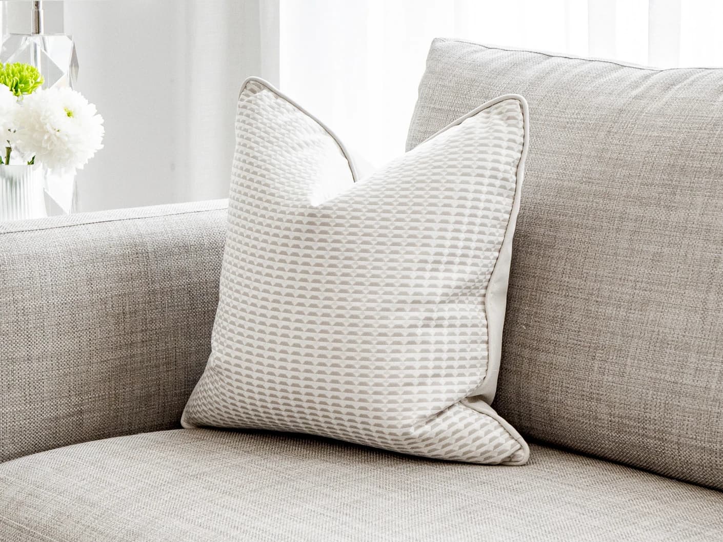 Paola Laurent single cushions in white and beige, shown in a lifestyle front view