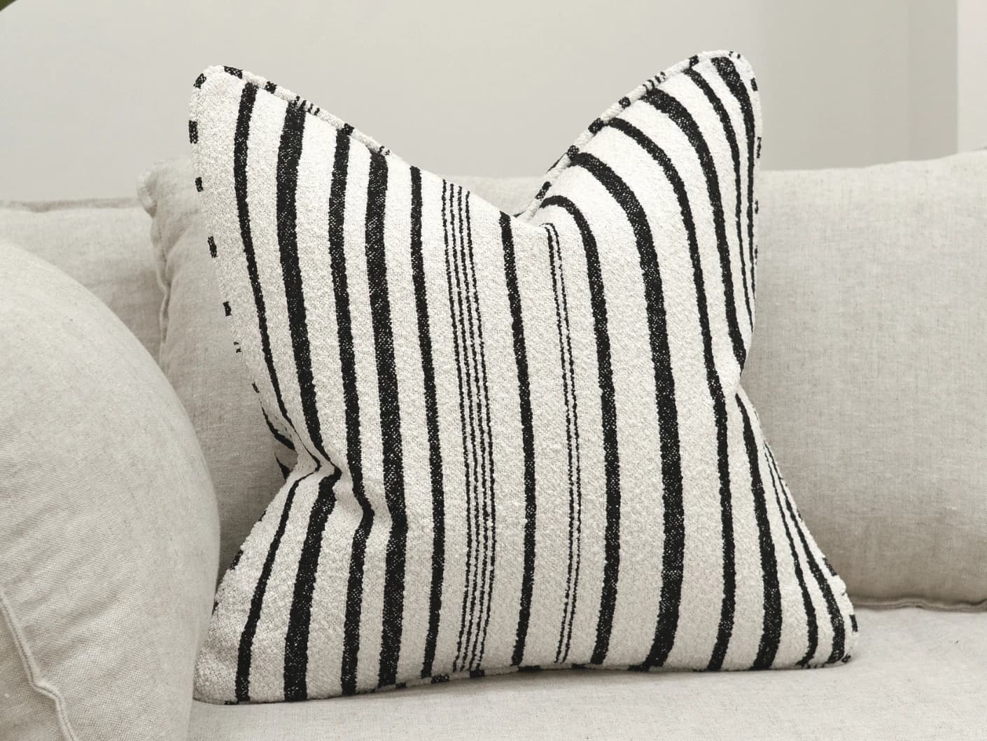 Raya Steele single cushions in ivory and charcoal, shown in a lifestyle front view