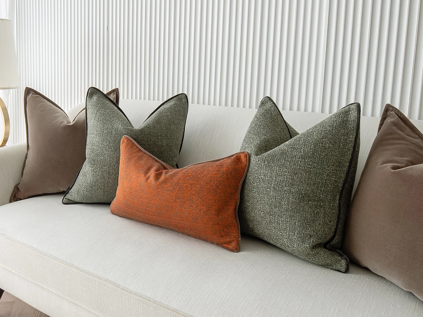 Roux Bundle bundle cushions in orange, brown and green, shown in a lifestyle front view