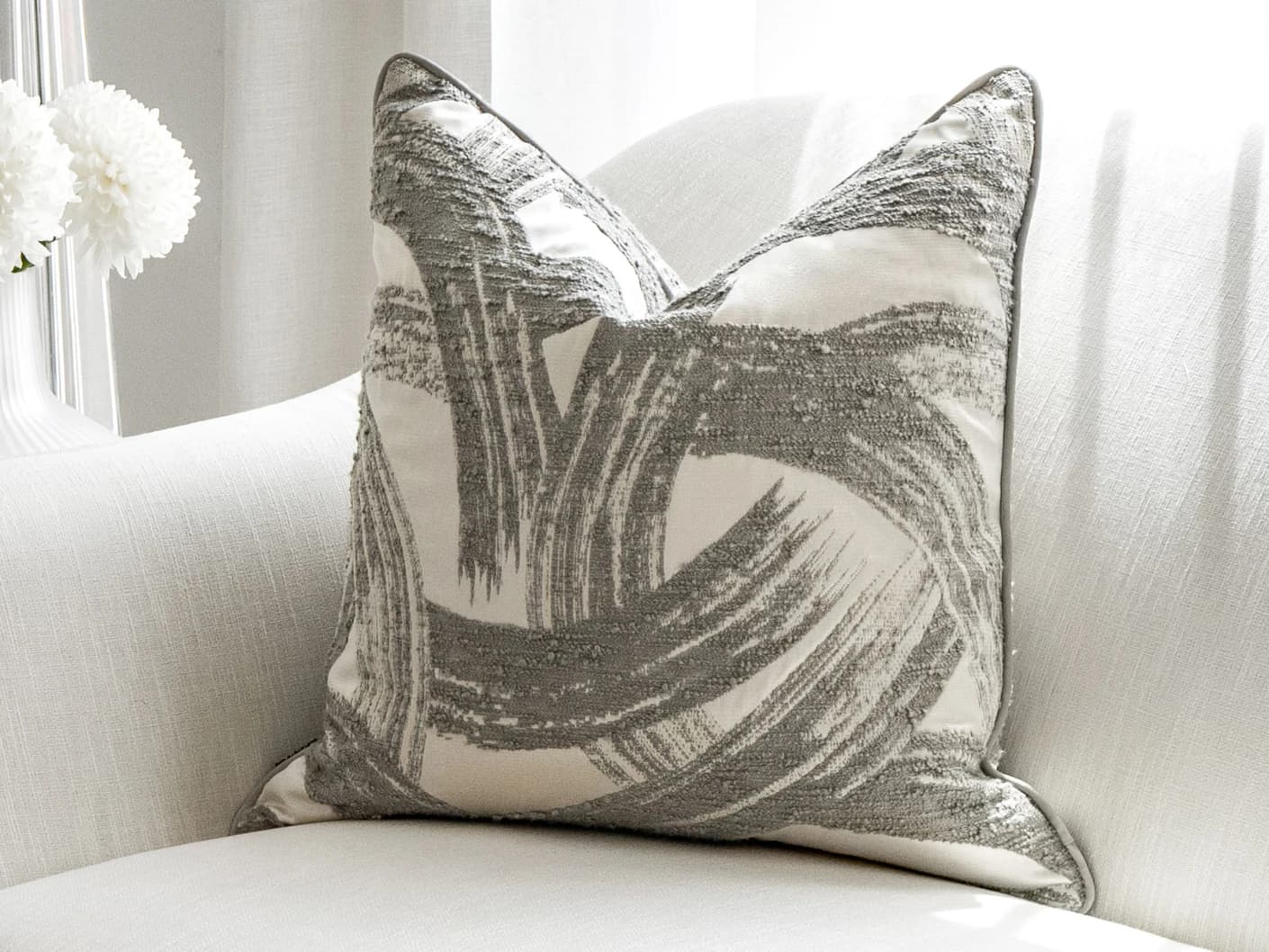 Tanya Laurent single cushions in white and grey, shown in a lifestyle front view
