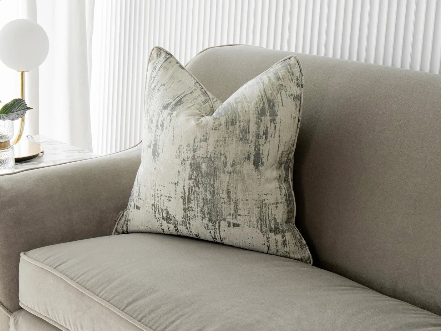 Theo Laurent single cushions in grey and white, shown in a lifestyle front view