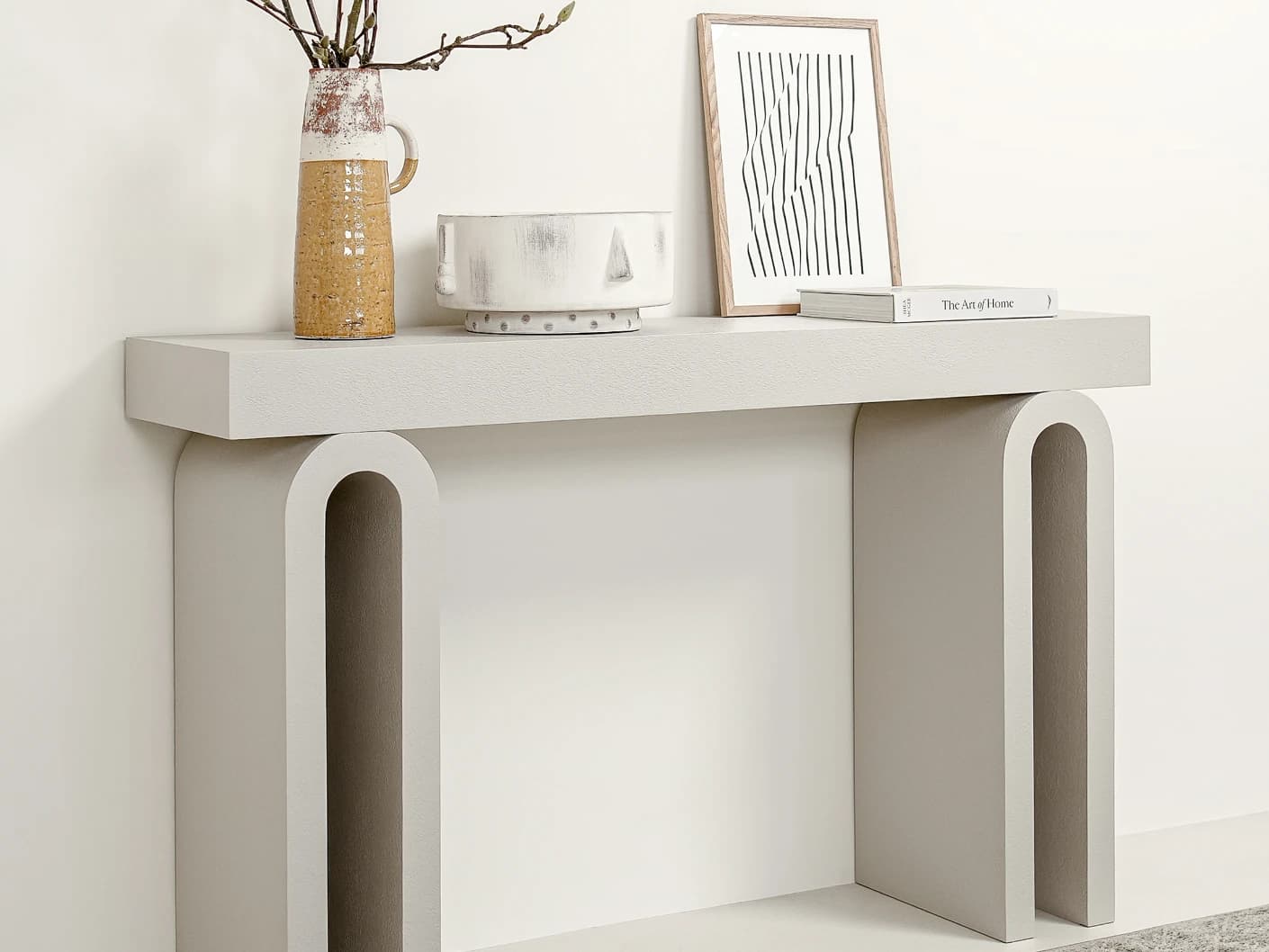 Trento console table in soft ivory and stone, shown in a lifestyle left view