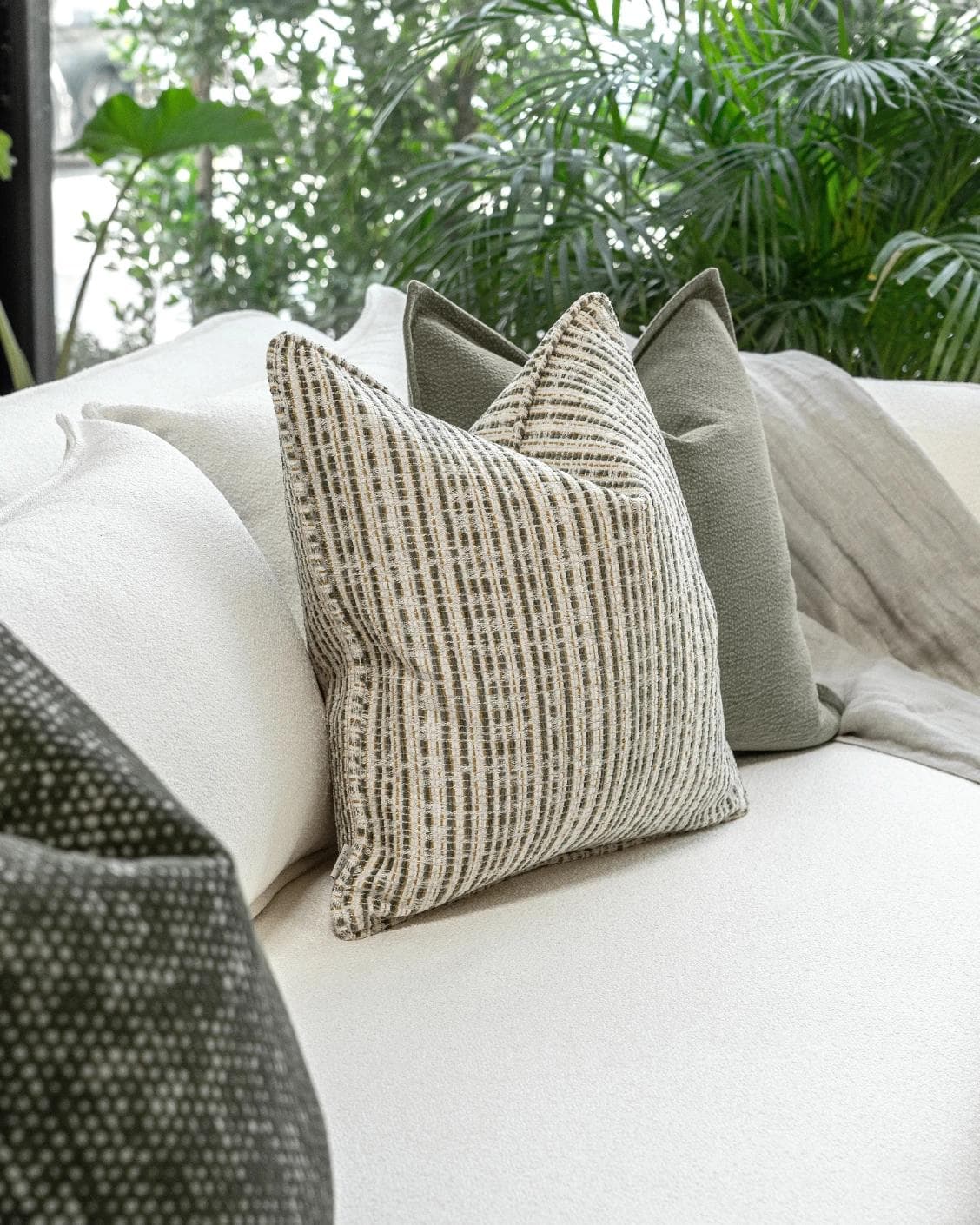Suki Bundle cushion in green and beige, shown in a lifestyle left view as image 5