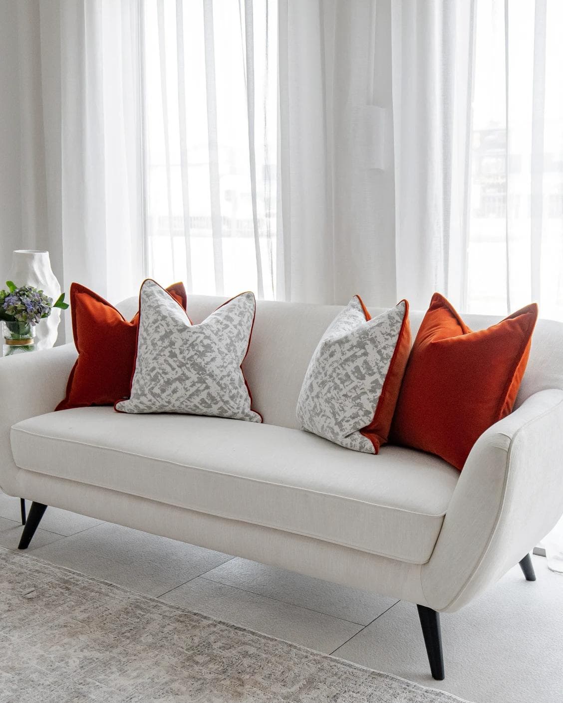 Braddy Bundle cushion in tan, orange, white and silver, shown in a lifestyle right view as image 2